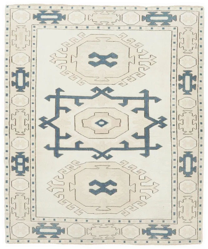 Full top view of the 5'3" x 6'5" ivory, blue, and tan geometric tribal rug on a white background.
