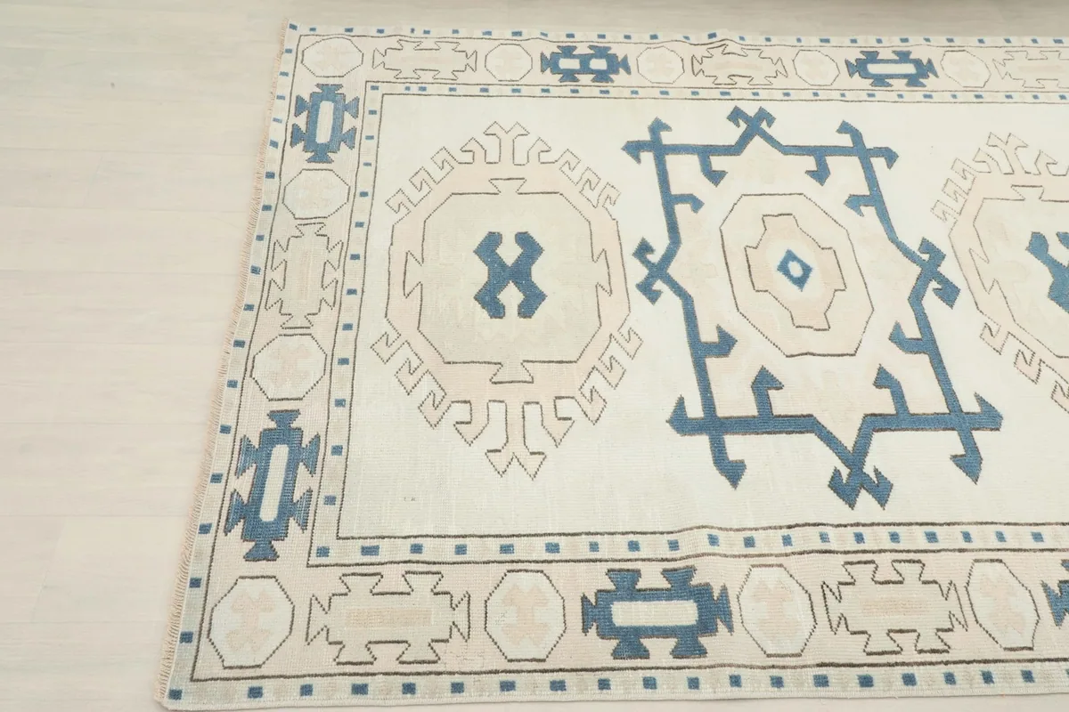 Close-up angle of one end of the rug, emphasizing the blend of ivory, blue, and tan colors.