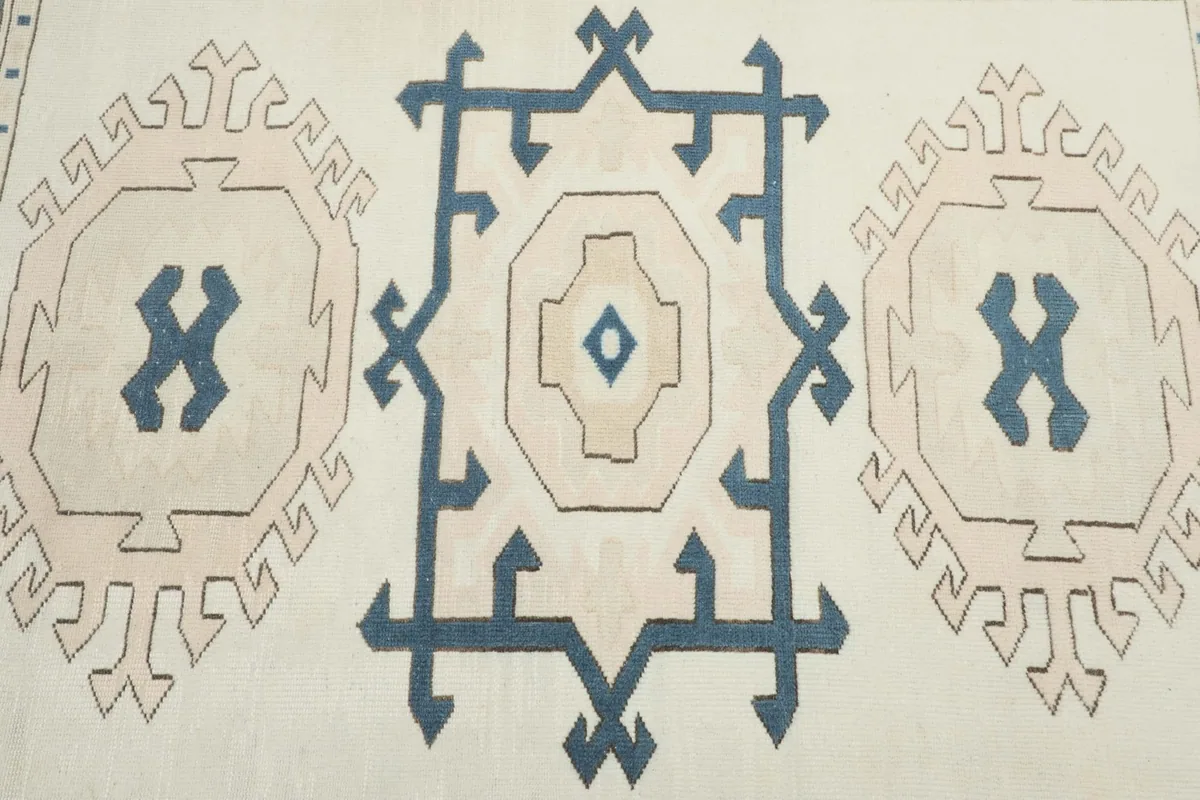 Detailed view of the central geometric medallion and surrounding tribal motifs on the ivory background.