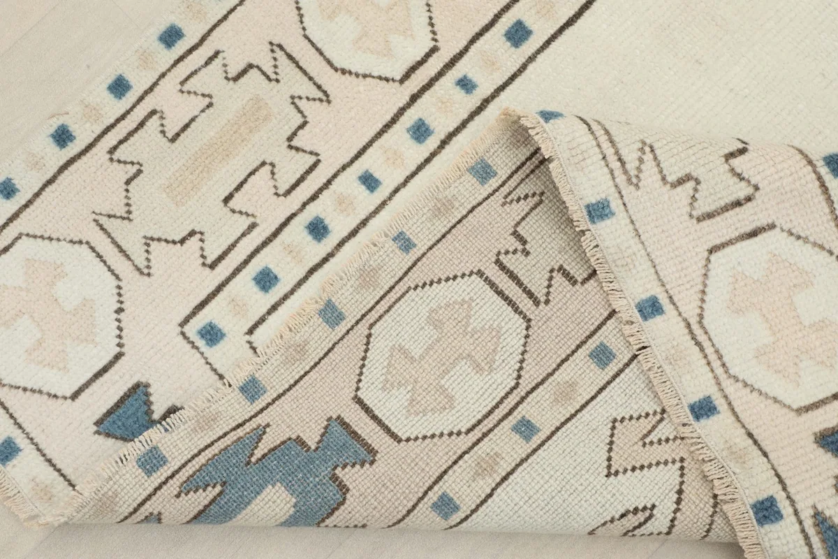 Corner of the rug folded back, revealing the hand-knotted construction and the reverse side.