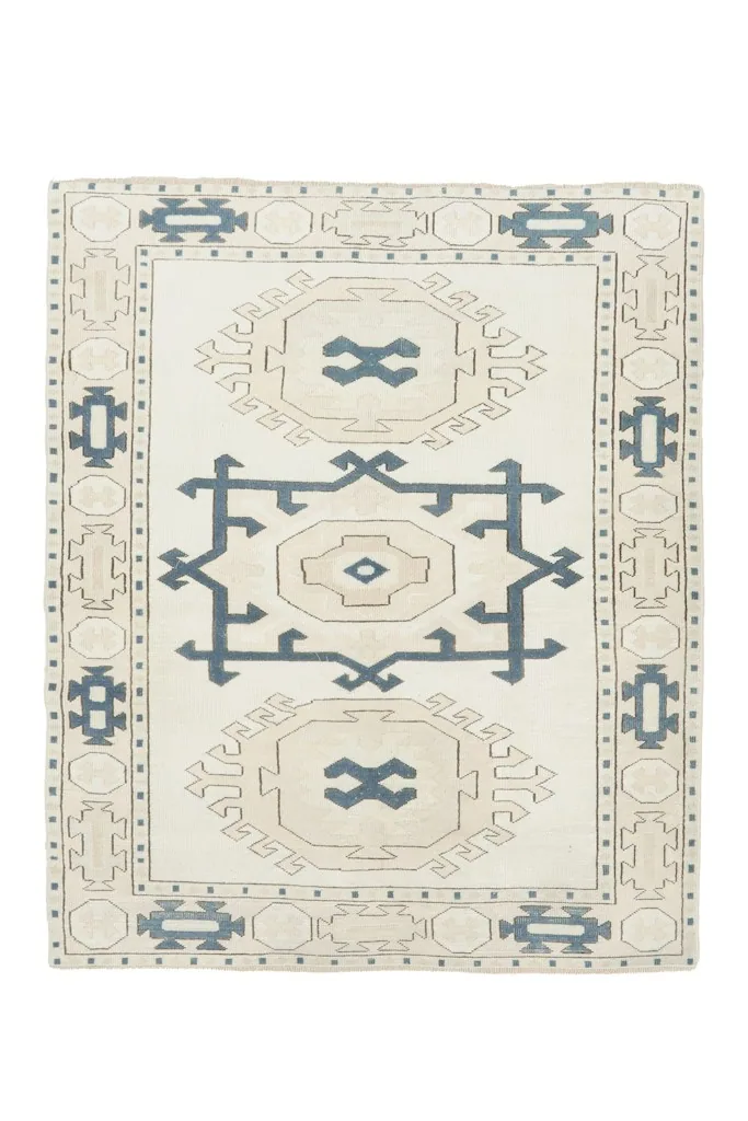 Overhead view of the vintage Anatolian rug, showcasing its ivory field with blue and tan patterns.
