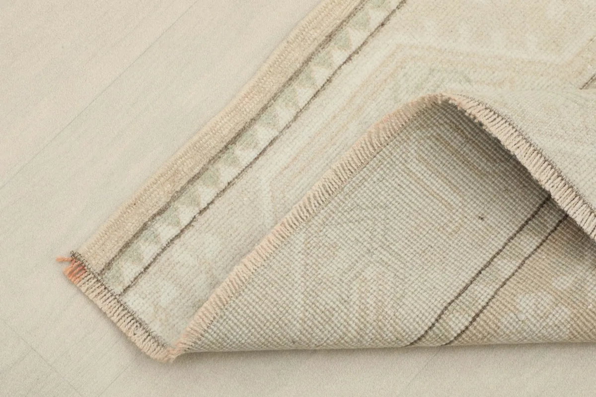 Corner of the rug folded to show the cotton foundation and the reverse side of the hand-knotted wool pile.