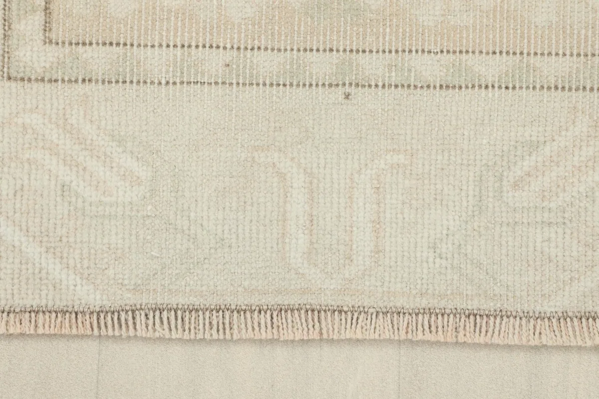 Close-up of the rug's fringe and the subtle geometric border pattern at one end.
