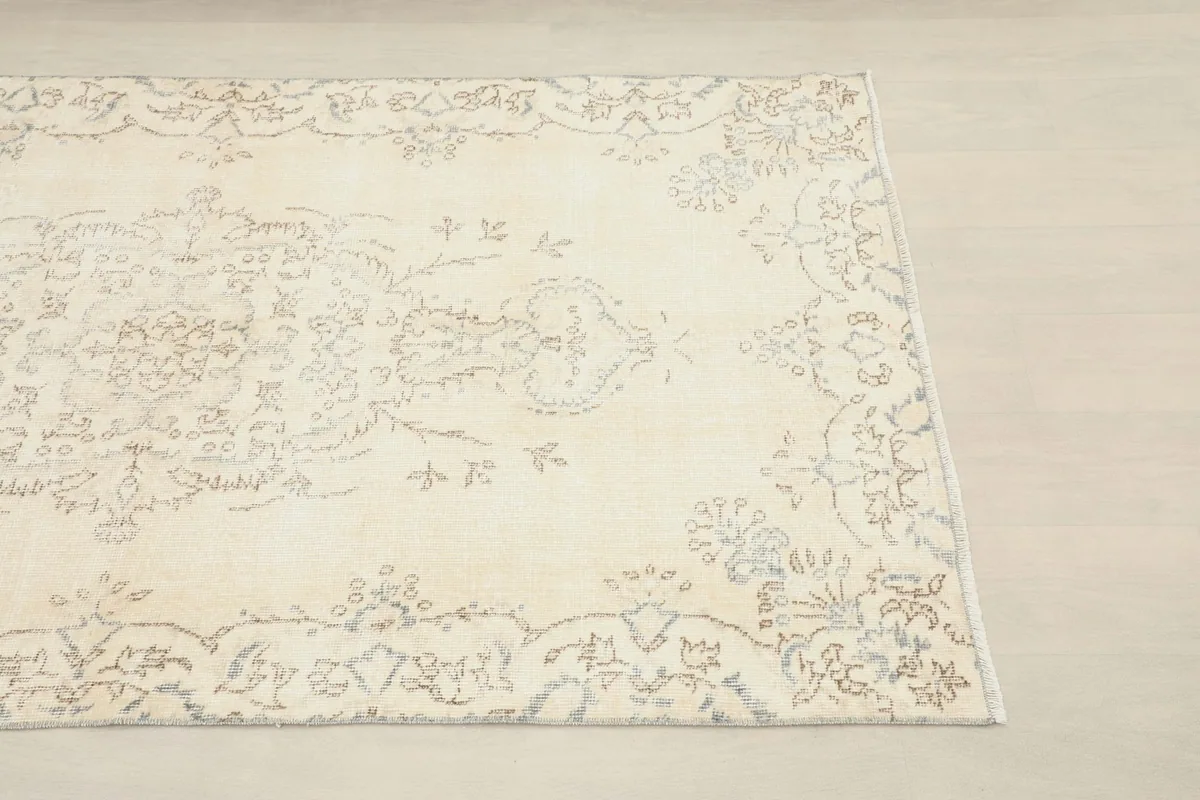 Close-up of the cream rug's corner, highlighting the faded border design