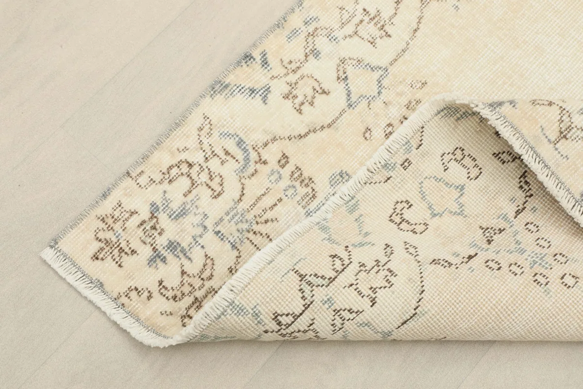 Corner of the rug folded back to show the wool pile and cotton foundation