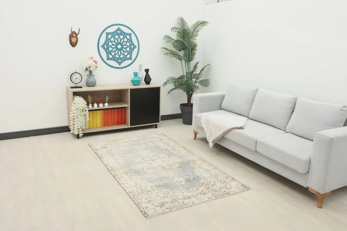 Vintage area rug displayed in a living room setting with a light gray sofa and wooden cabinet