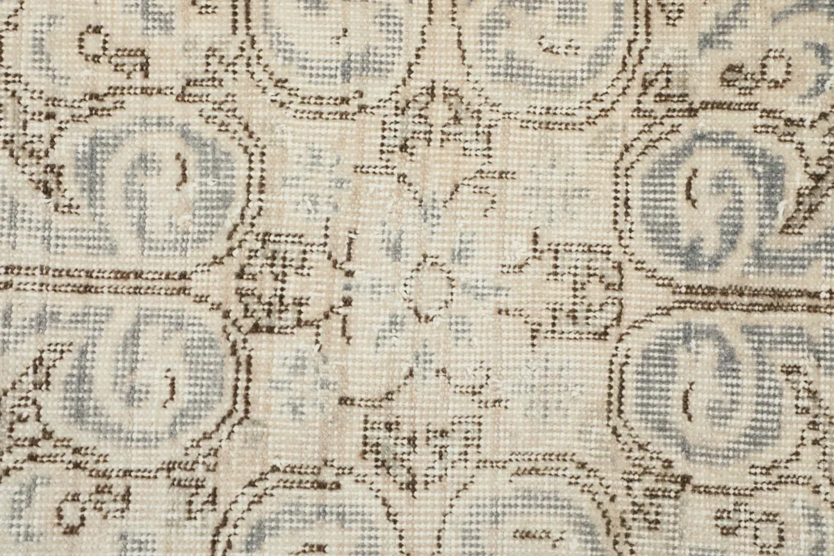 Close-up of the wool pile texture and subtle variations in the ivory and blue patterns