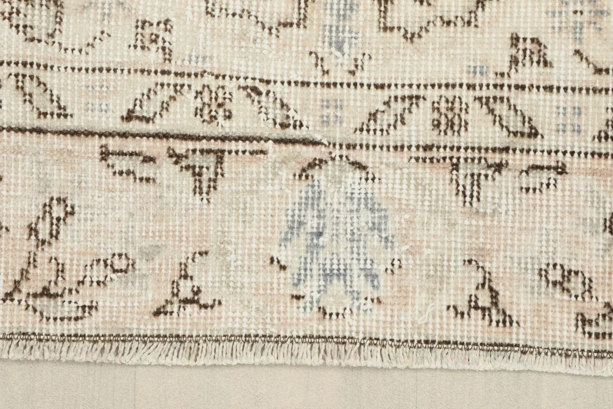 Detail of the rug's border showing fringe and the patterned edge with light wear