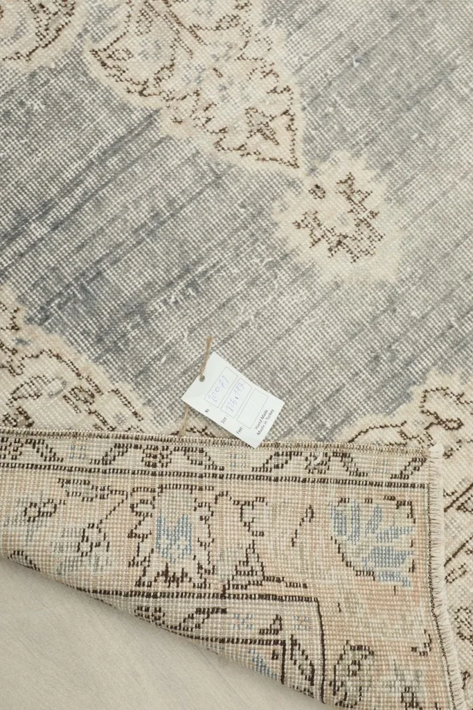 Underside of the vintage rug with a tag, showing the hand-knotted cotton foundation