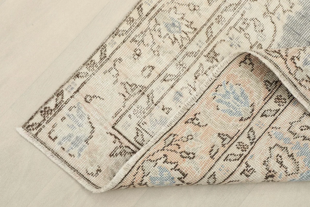 Corner of the vintage rug folded back, revealing the backside and construction details