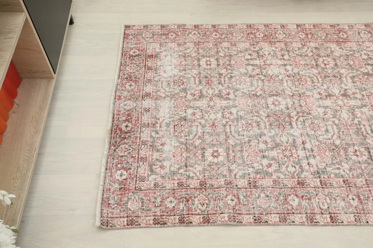 Overhead angle showing the rug's faded rose and gray colors and detailed border design