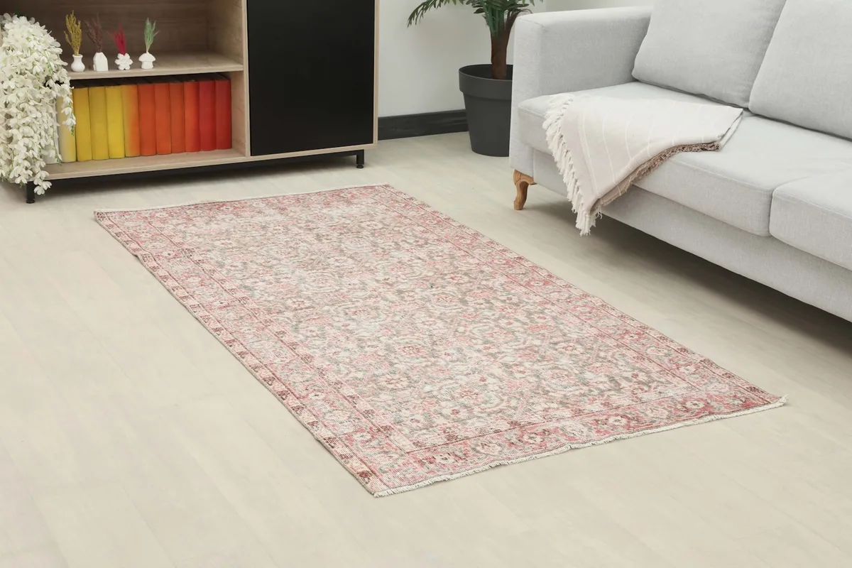 Angle view of the rose and gray rug in a living room, showing its placement next to a sofa