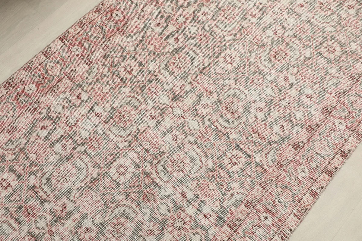 Detailed view of the rug's surface, revealing the intricate floral and geometric motifs and low pile