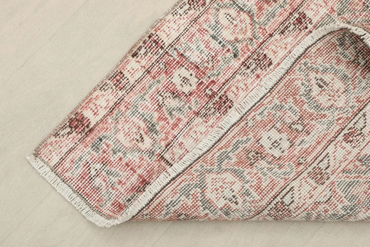 Corner of the rug folded to show the wool pile on cotton foundation and fringe
