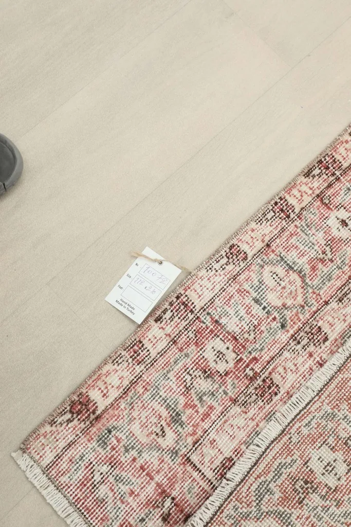 Close-up of the rug's label and a rolled corner, indicating its origin and material