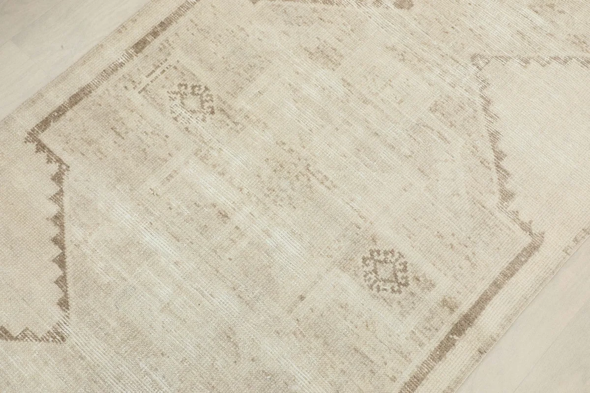 Overhead detail of the central geometric pattern and subtle color variations on the ivory field