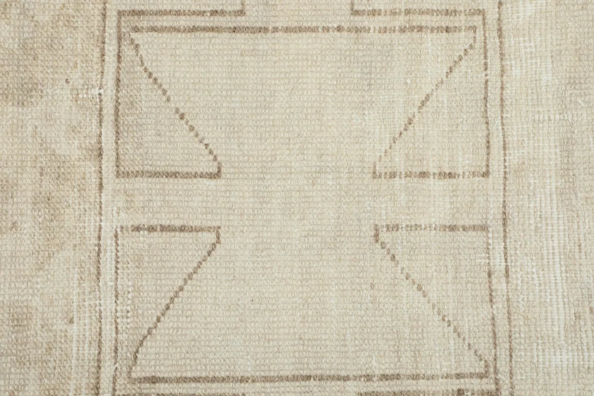 Close-up of the hand-knotted wool pile and the intricate tan geometric design