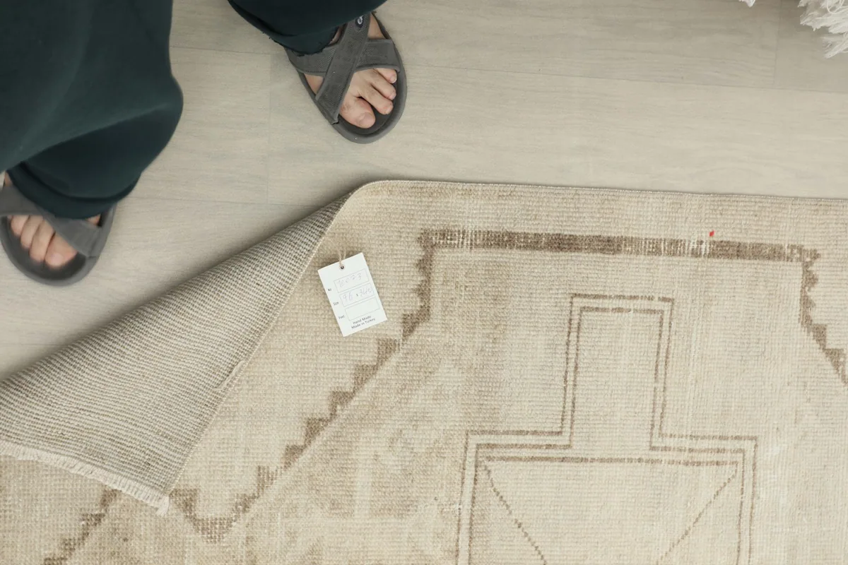 A person's feet next to the runner, showing the rug's scale and a tag on the back