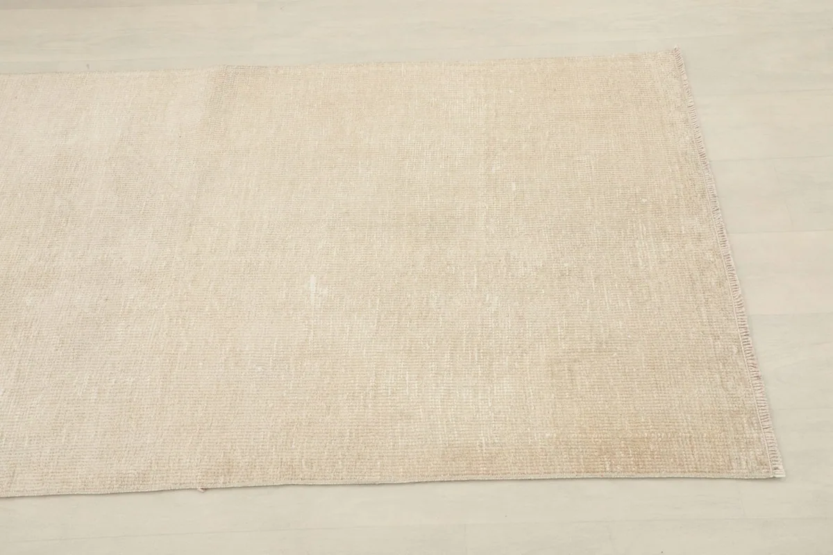 Close-up of one end of the cream wool runner, showing the subtle texture and slight variations in tone