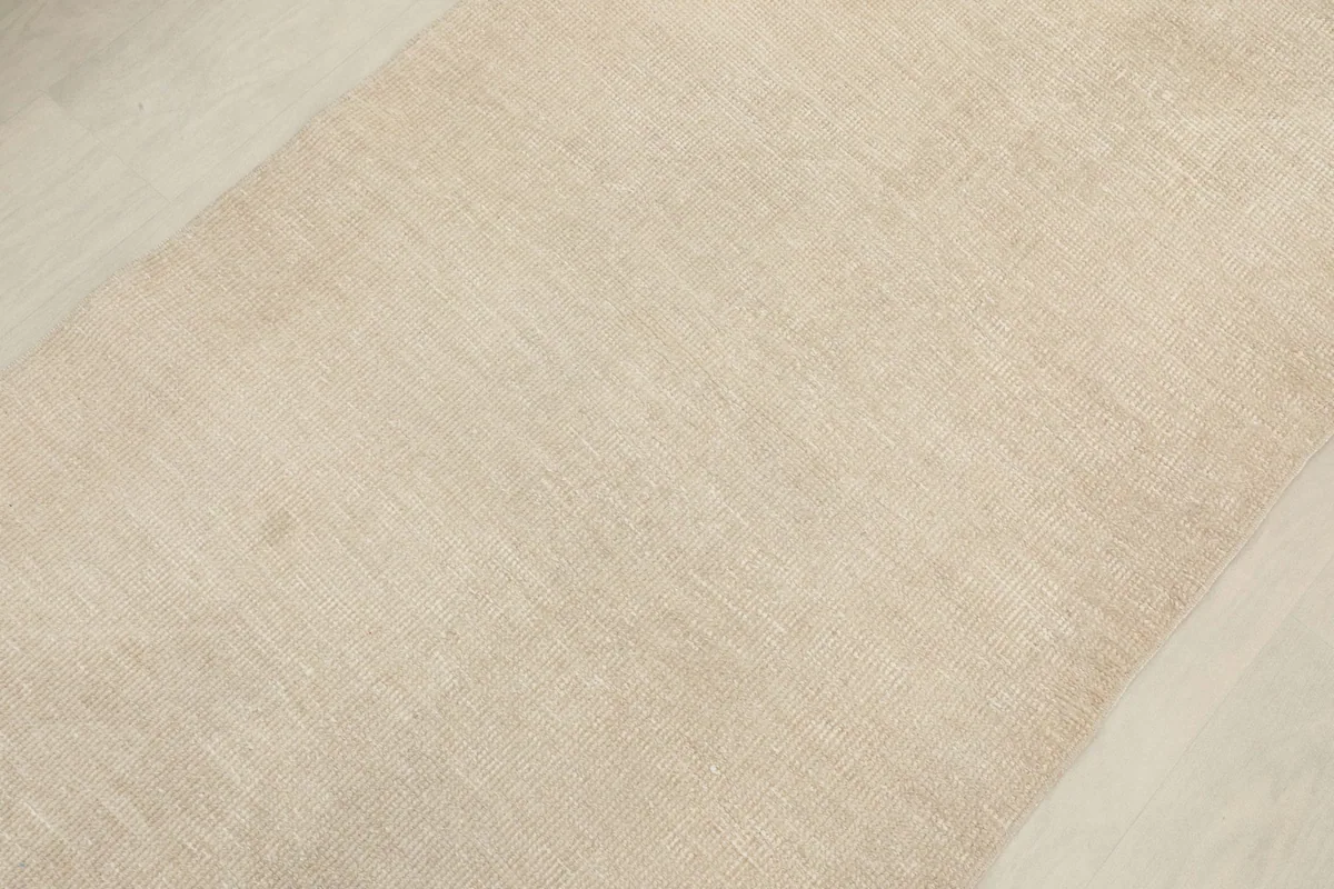 Angled detail shot of the low wool pile surface of the cream runner, revealing its soft texture