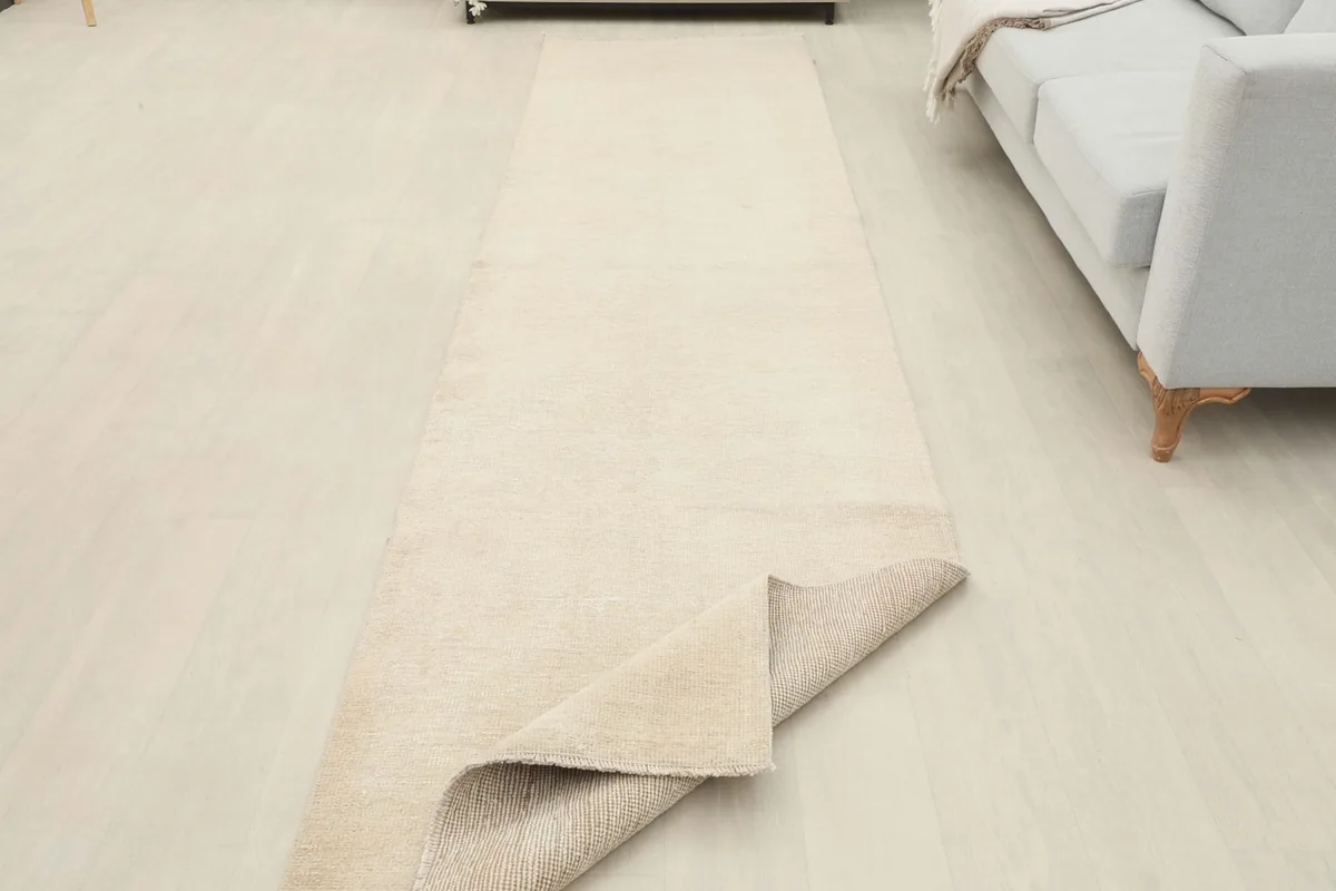 The cream runner partially folded in a room setting, revealing the back of the rug