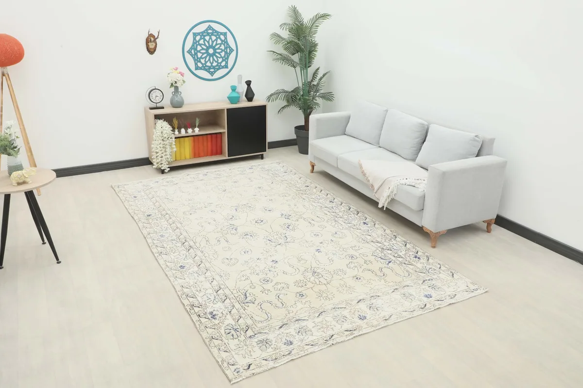 Ivory blue floral vintage rug displayed in a living room setup with a gray sofa