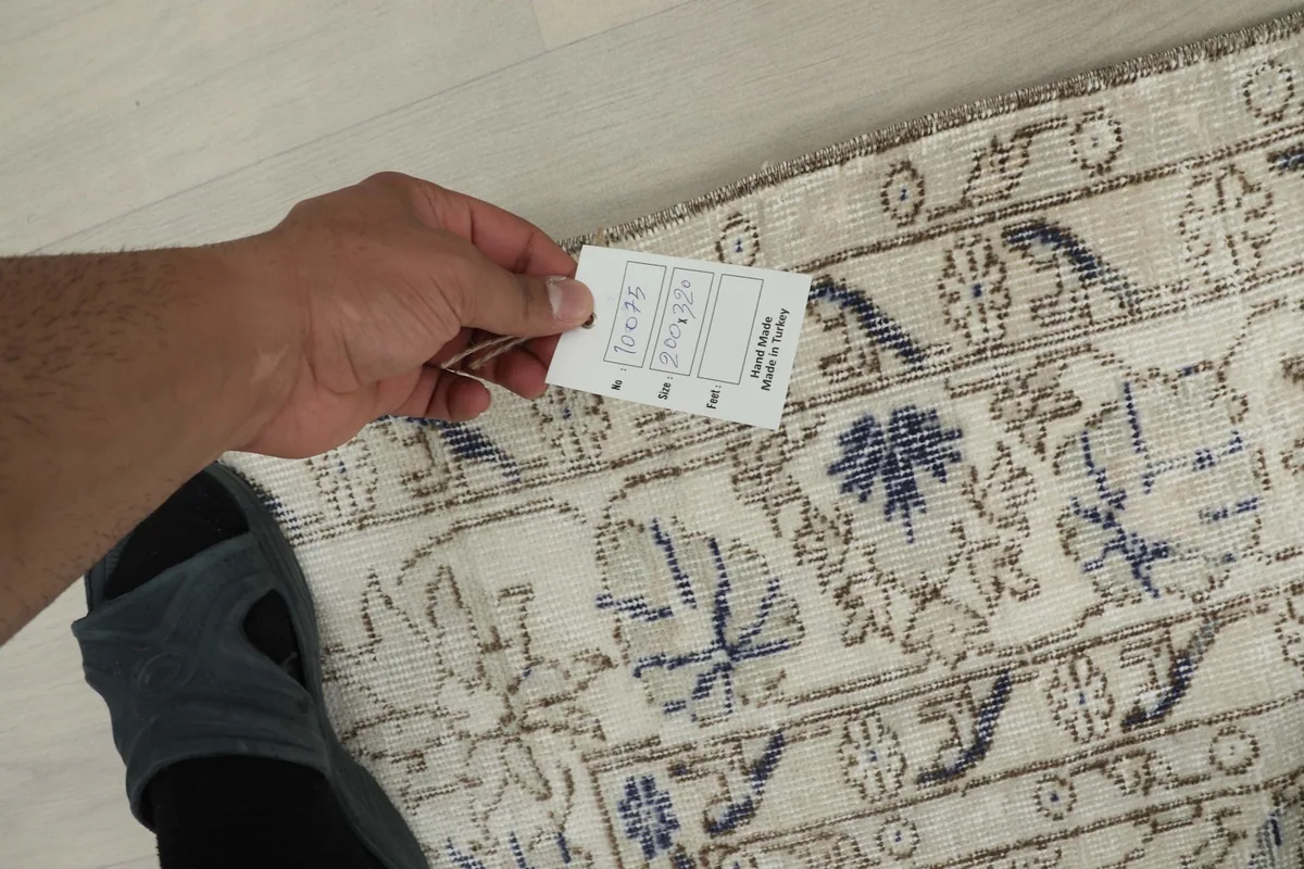 Hand holding a tag, showing the texture and weave of the vintage wool rug