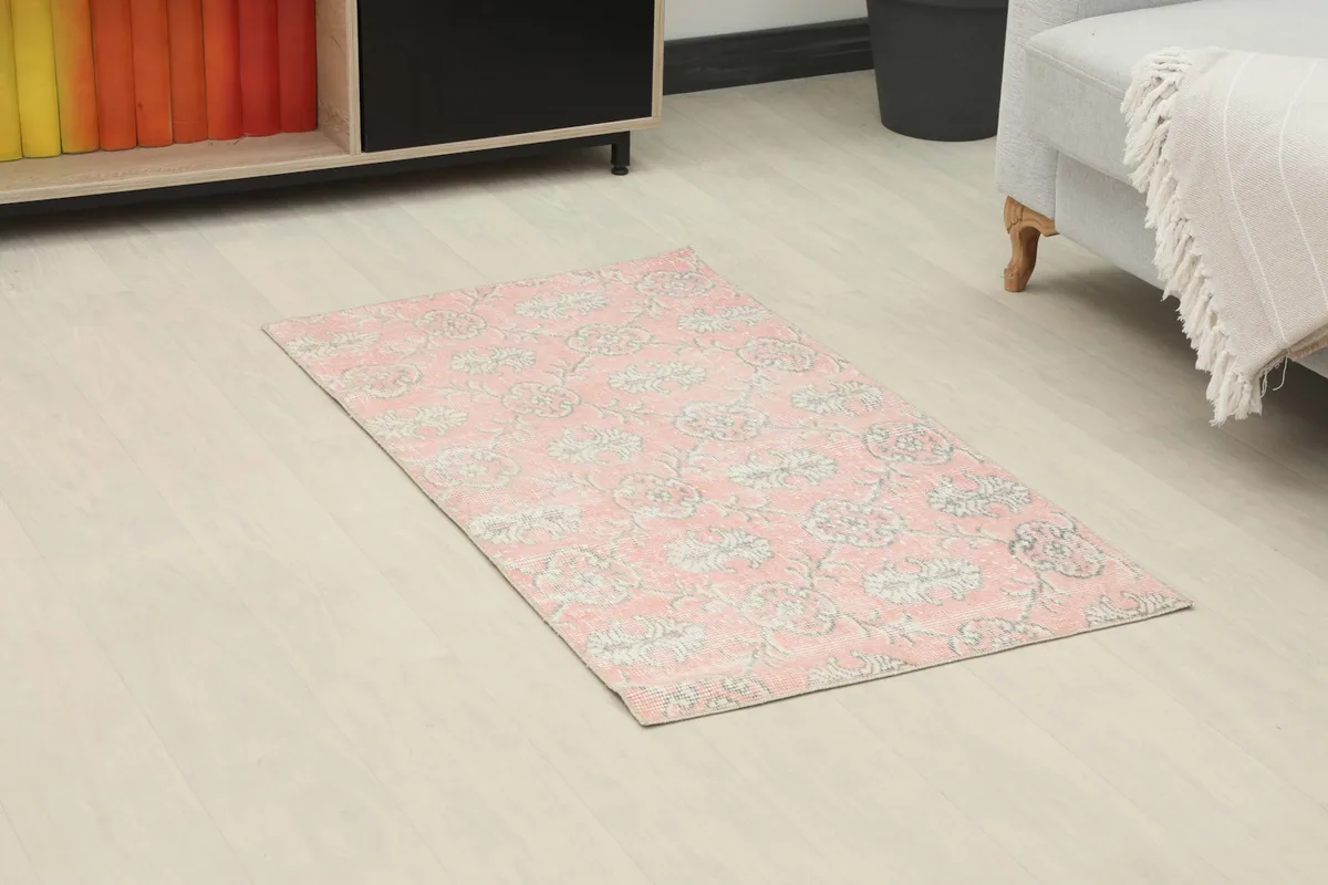 Overhead view of the pink floral rug in a room, showing its placement near a sofa and cabinet.