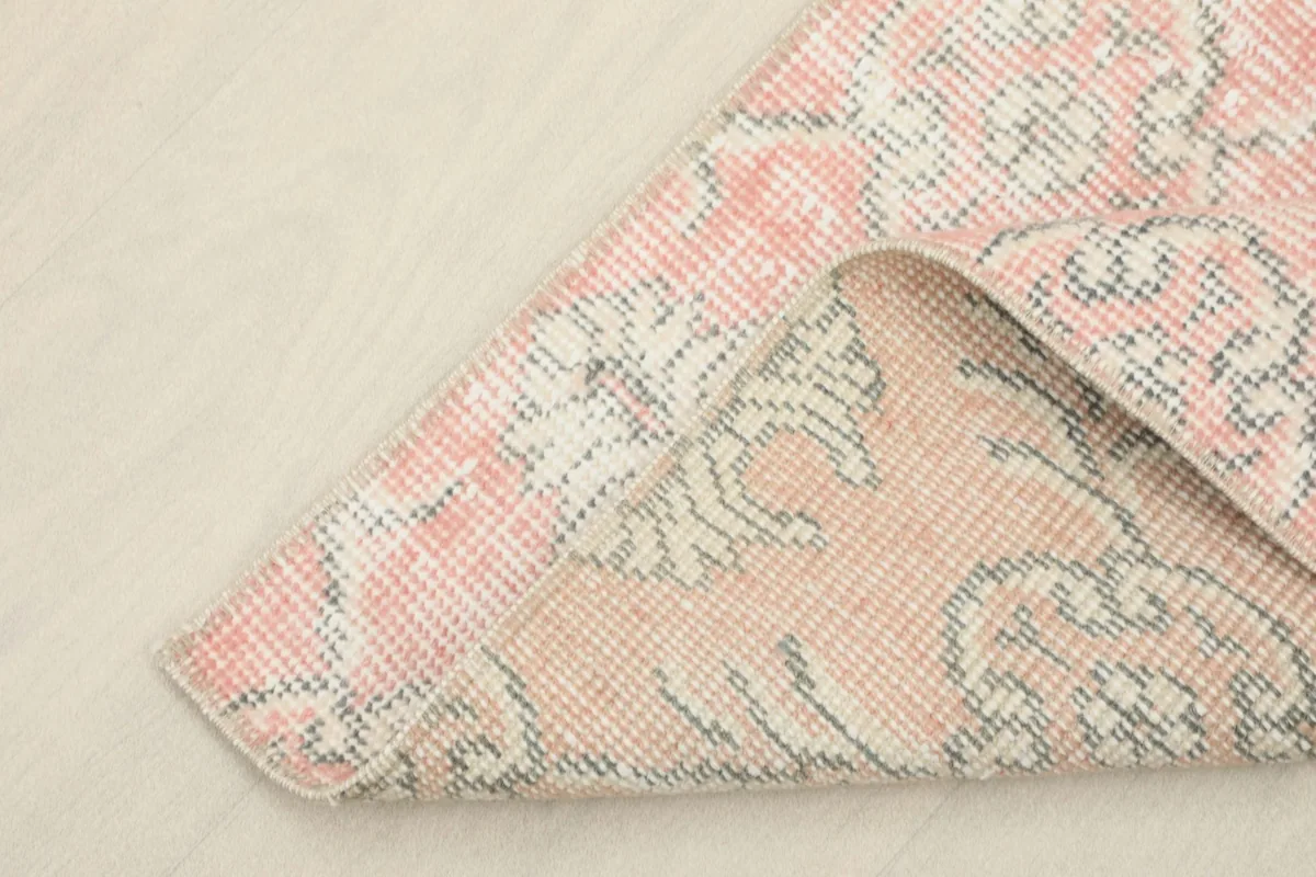 Corner of the rug folded back, revealing the hand-knotted cotton foundation and reverse side of the wool pile.