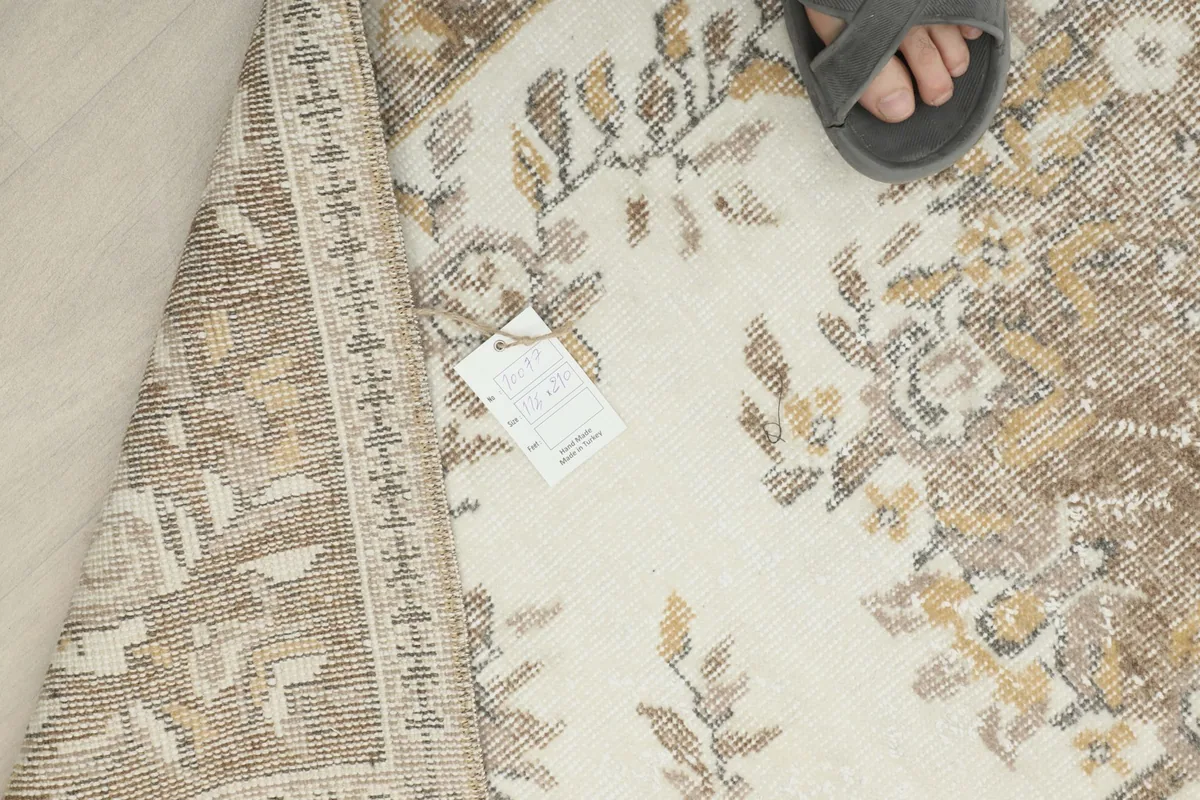 View of the rug's reverse side and label, with a foot for scale