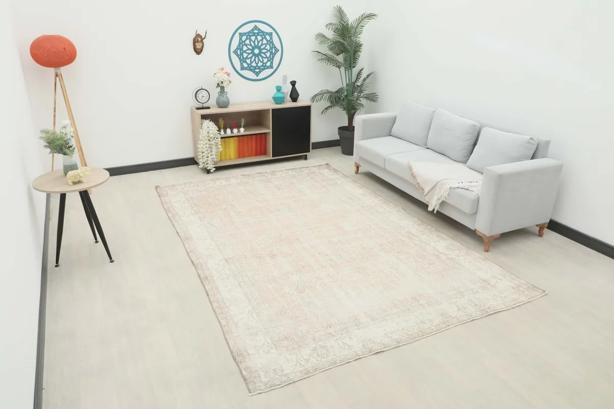 Large Anatolian rug with muted rose and beige tones in a living room setting with a light gray sofa.