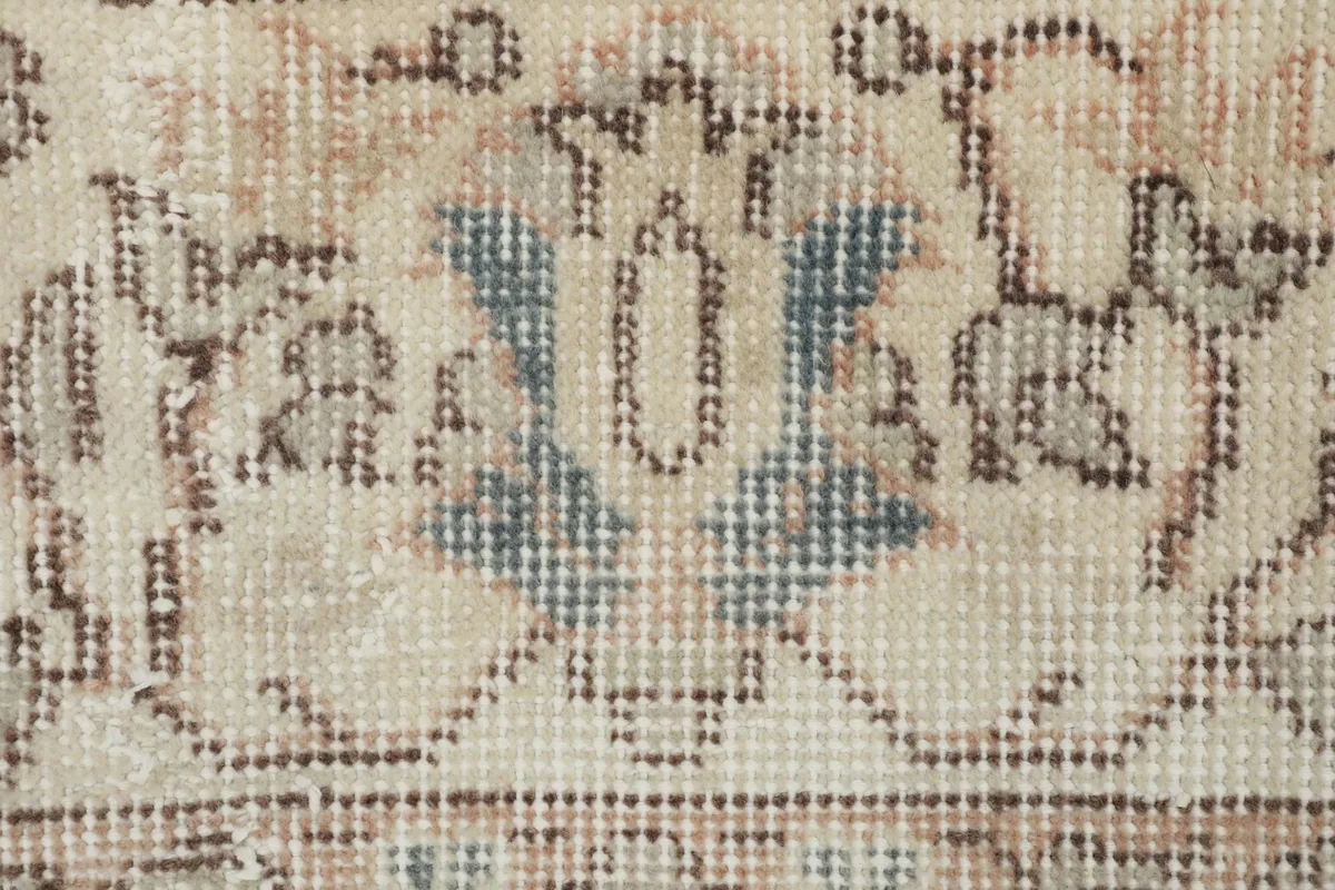 Detailed view of a motif within the rug, showcasing the hand-knotted wool pile and hints of blue.