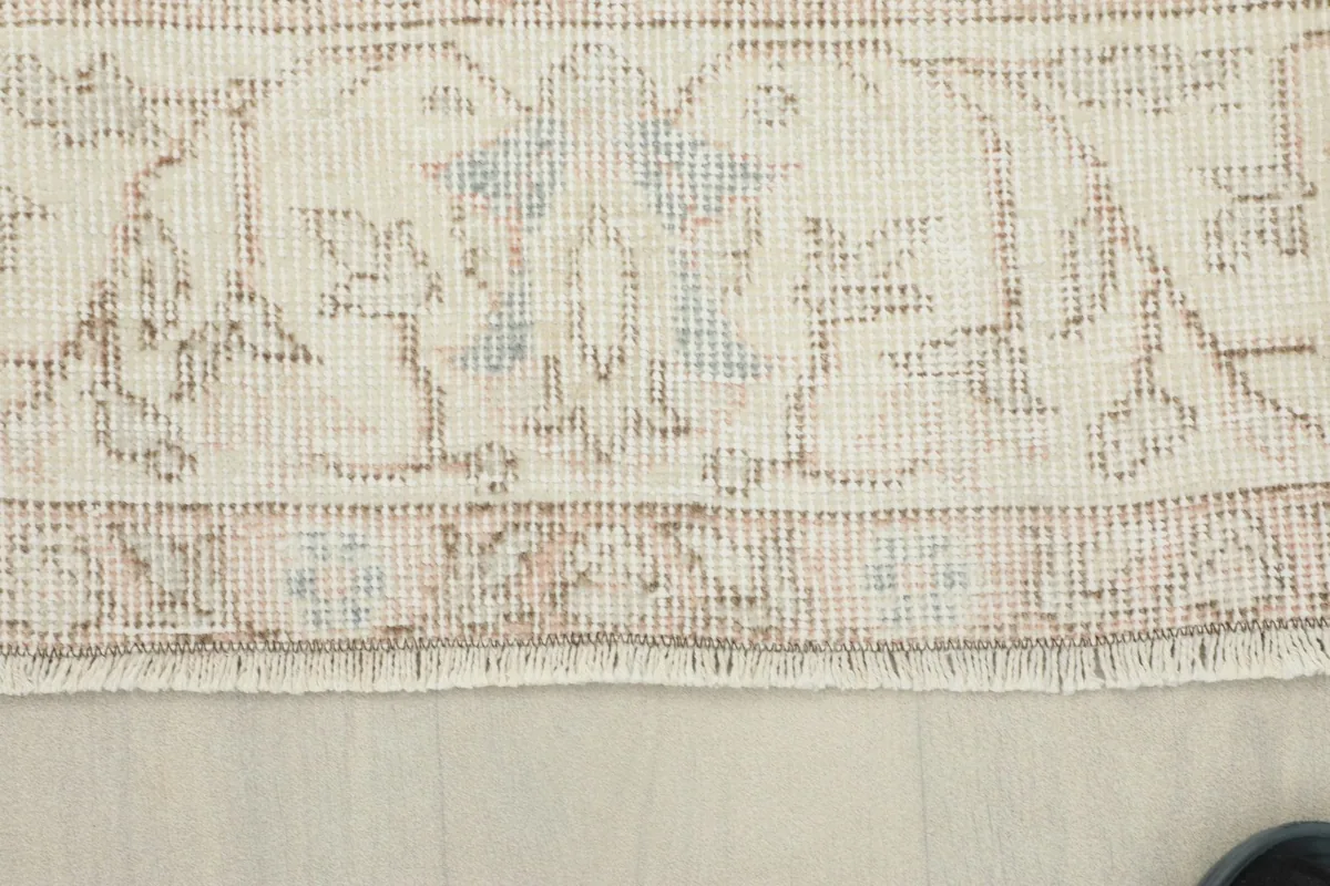 Close-up of the rug's edge, revealing the short fringe and the texture of the low wool pile.