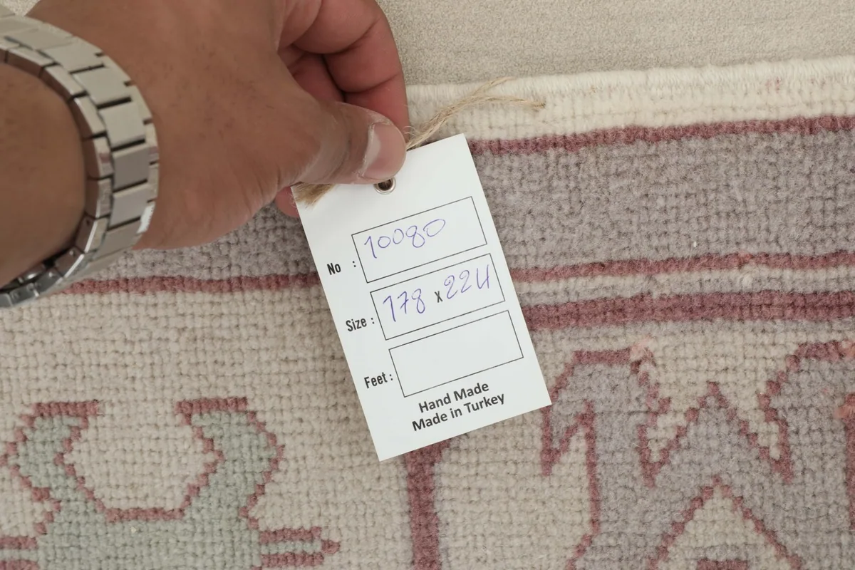 Hand holding a tag showing the rug's item number and size in centimeters