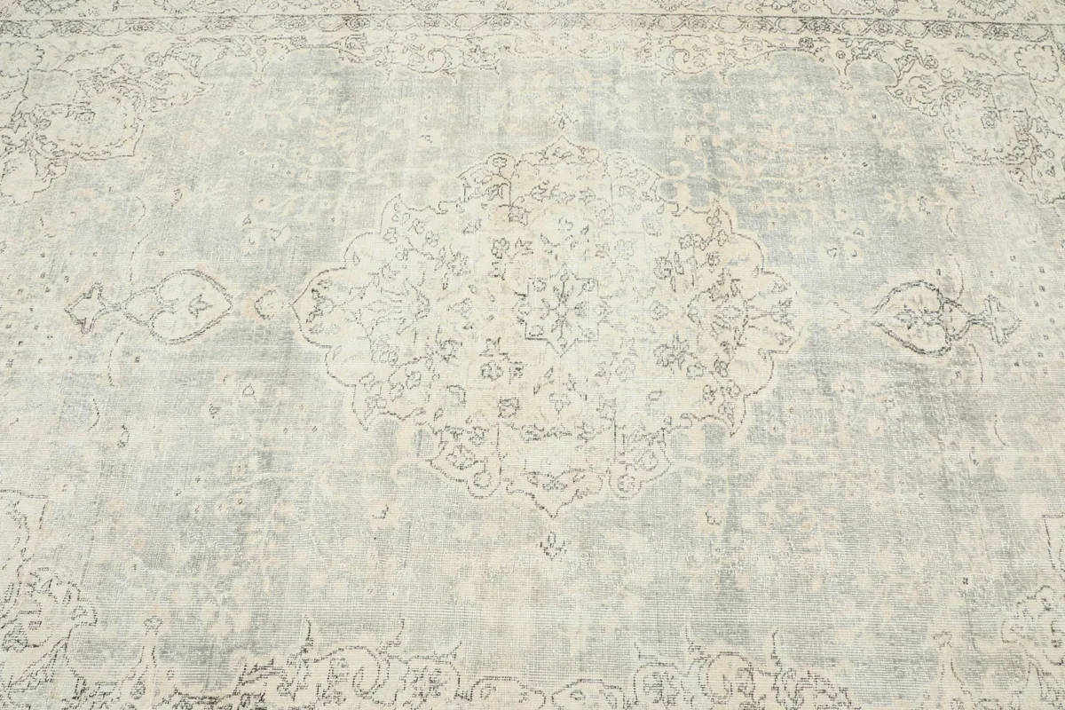 Close-up of the central medallion and surrounding floral motifs in gray on the cream background.