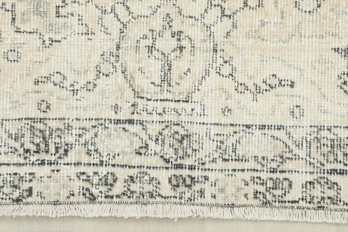 Close-up of the rug's border, showcasing the detailed gray floral design and short fringe.