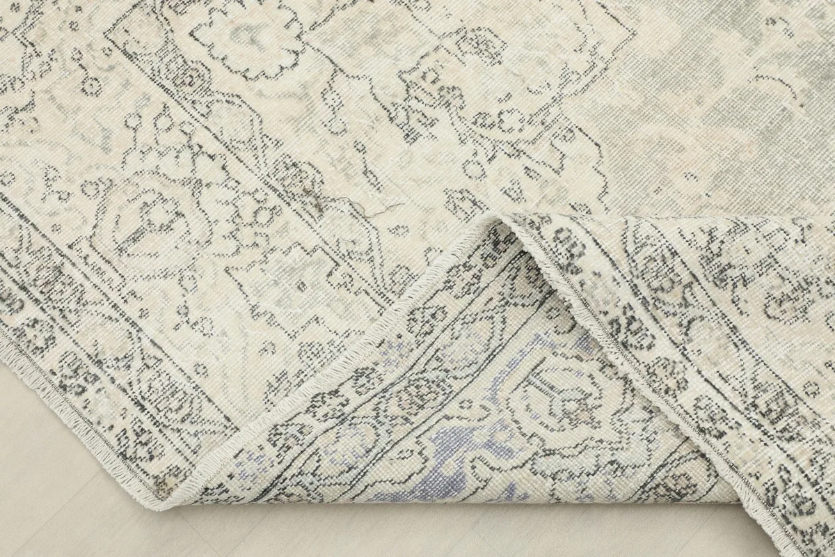 Folded corner of the rug, revealing the wool pile and cotton foundation, with subtle color shifts.