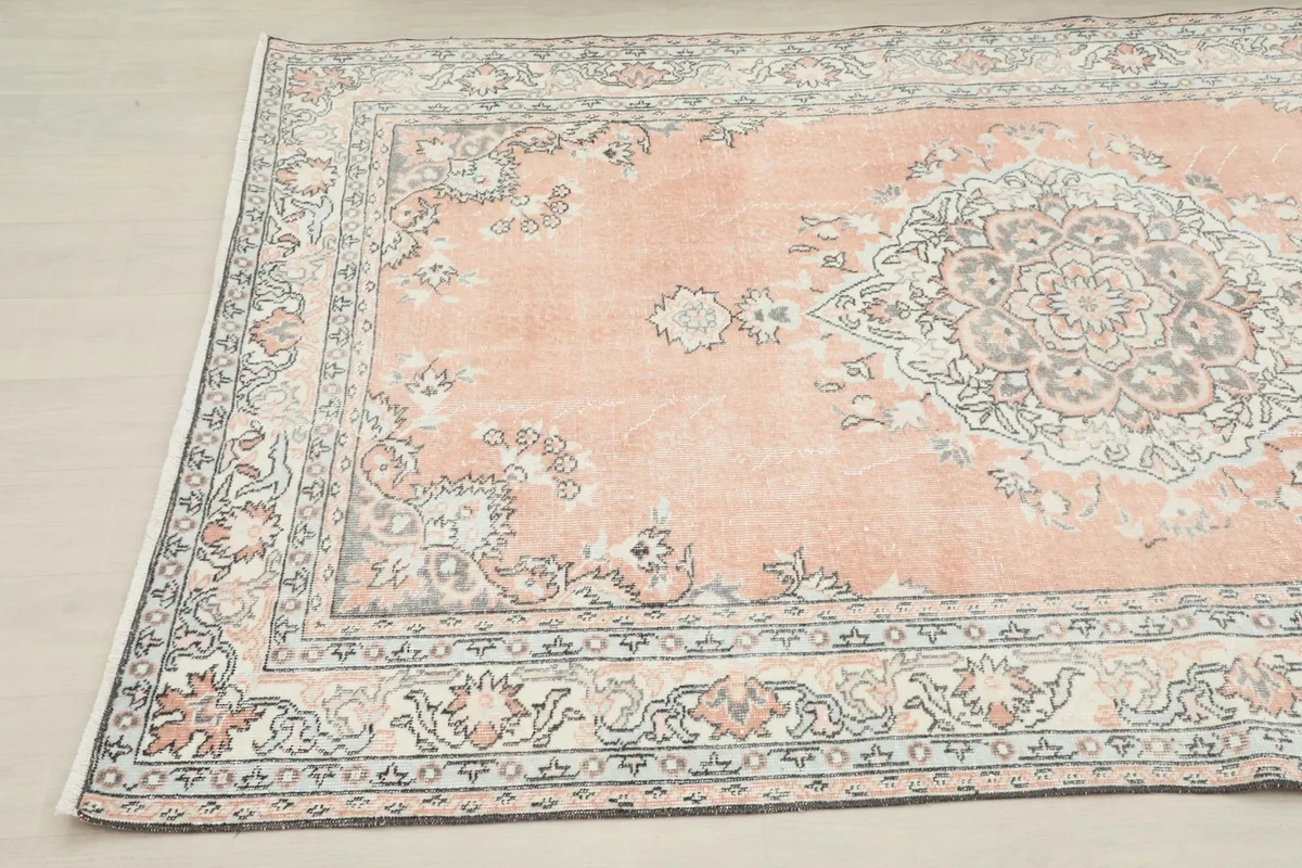 Angled view of the rose vintage Anatolian rug, capturing the border and medallion