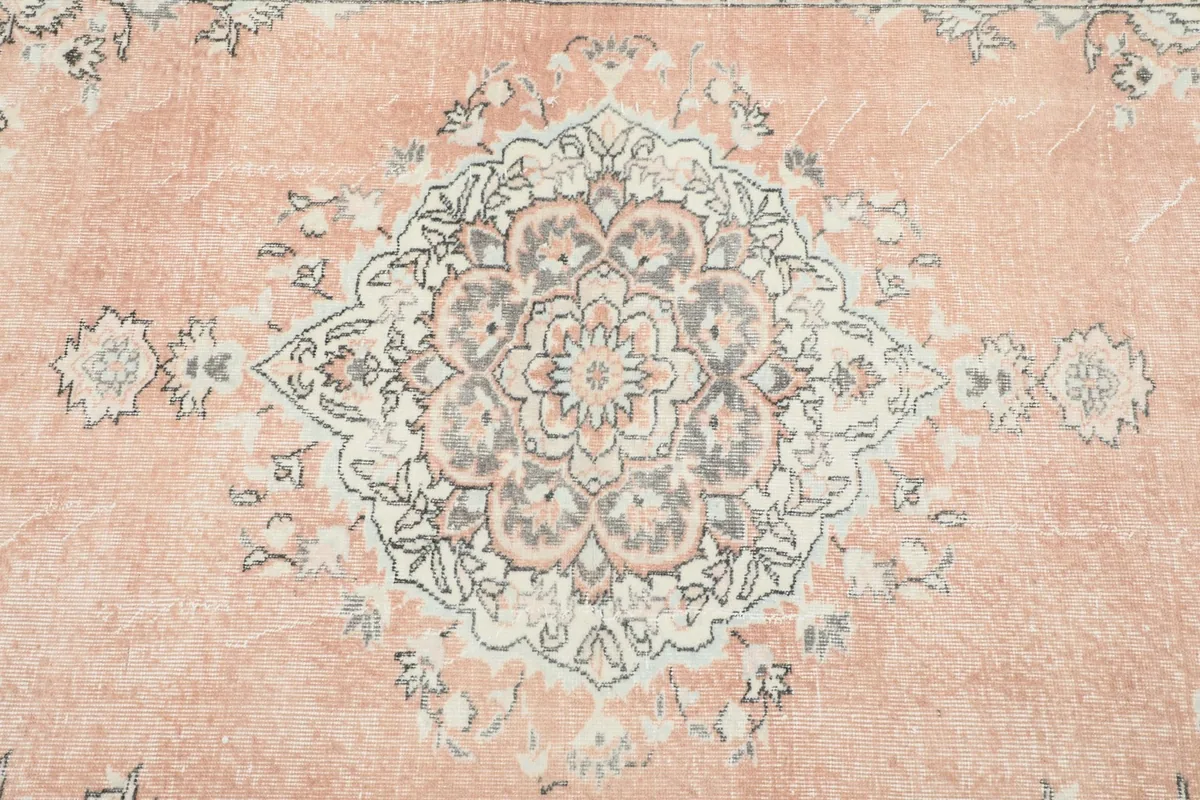 Close-up detail of the central medallion design in cream and gray on the rose field