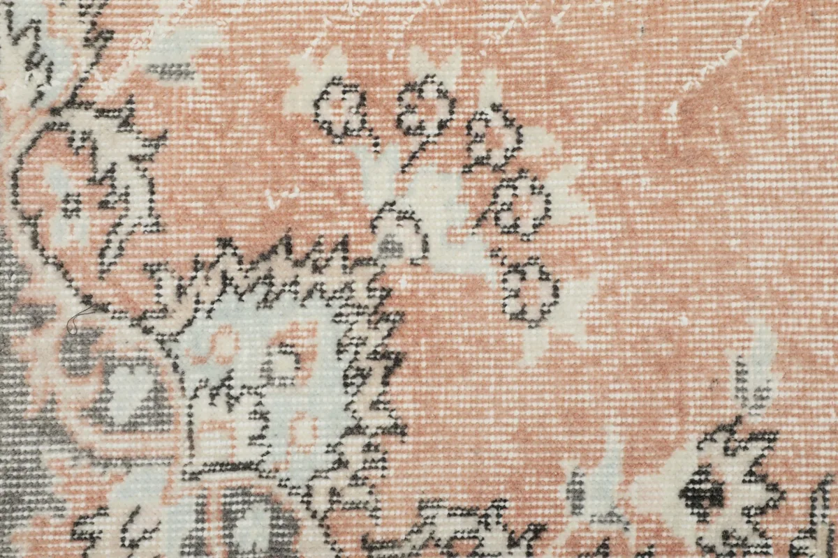 Detailed view of the floral and geometric motifs within the rose field of the rug