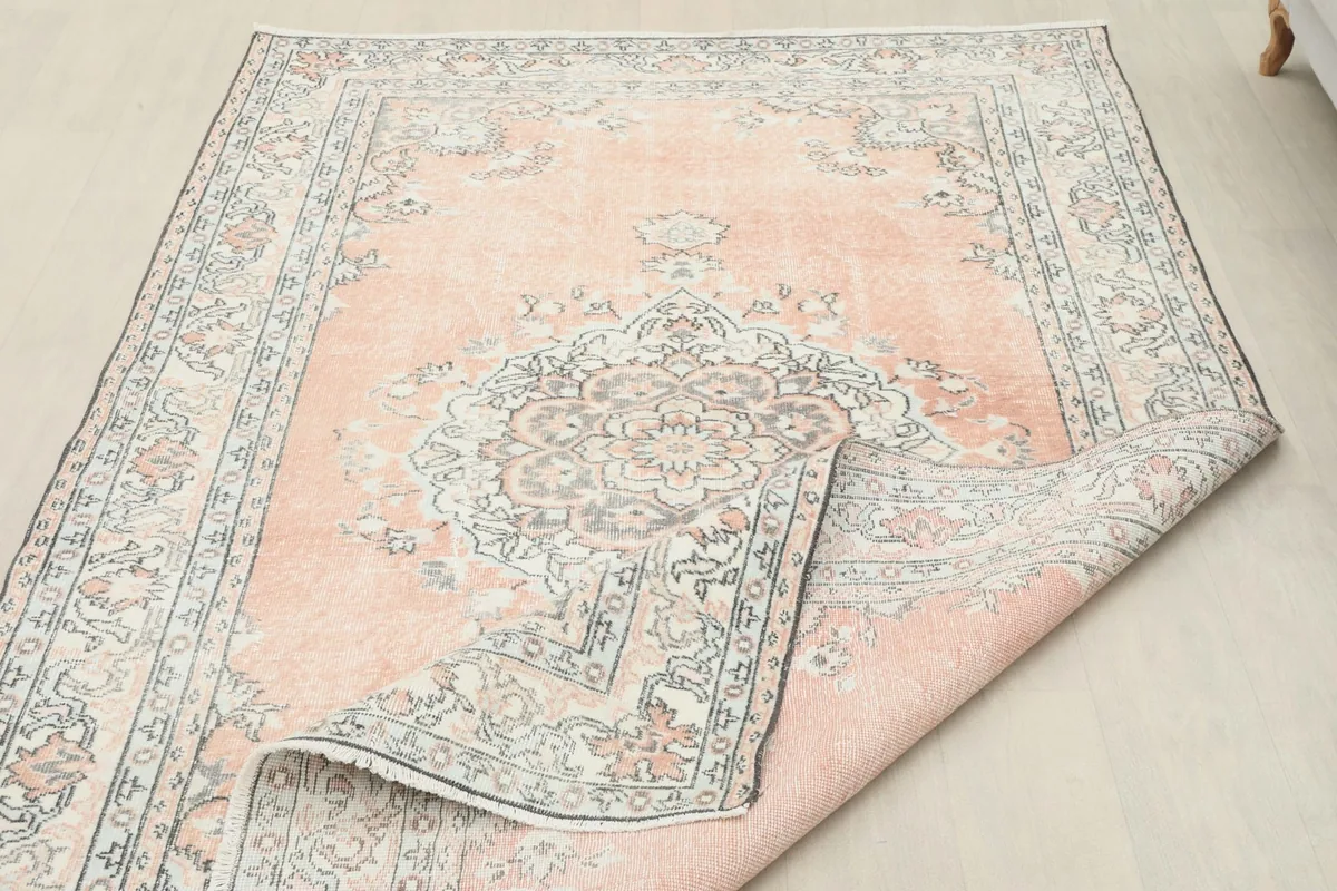 Side view of the rug with a corner folded, showing the low wool pile and fringe