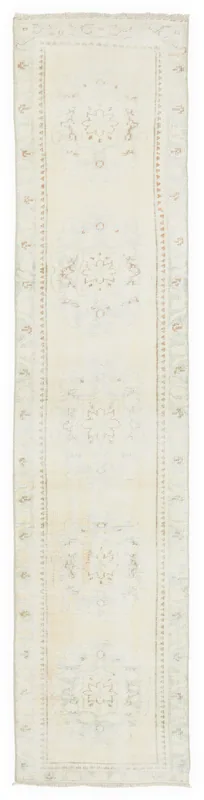 Full top view of the 2'5" x 11'7" vintage Anatolian runner with a cream field and faded motifs.