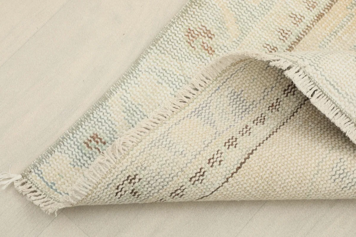 Corner of the rug folded to show the hand-knotted back and the cotton foundation weaving.