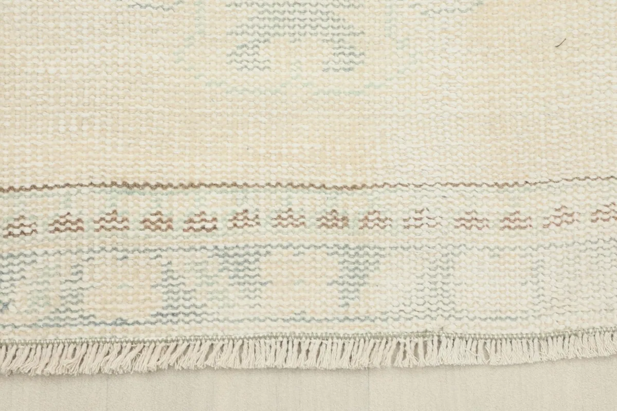 Close-up of the rug's fringe and a section of the border, revealing the wool pile and cotton foundation.