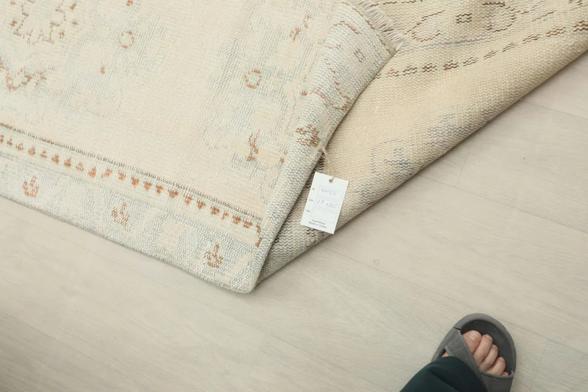 Corner of the rug with a product tag, displaying the hand-knotted construction and vintage character.