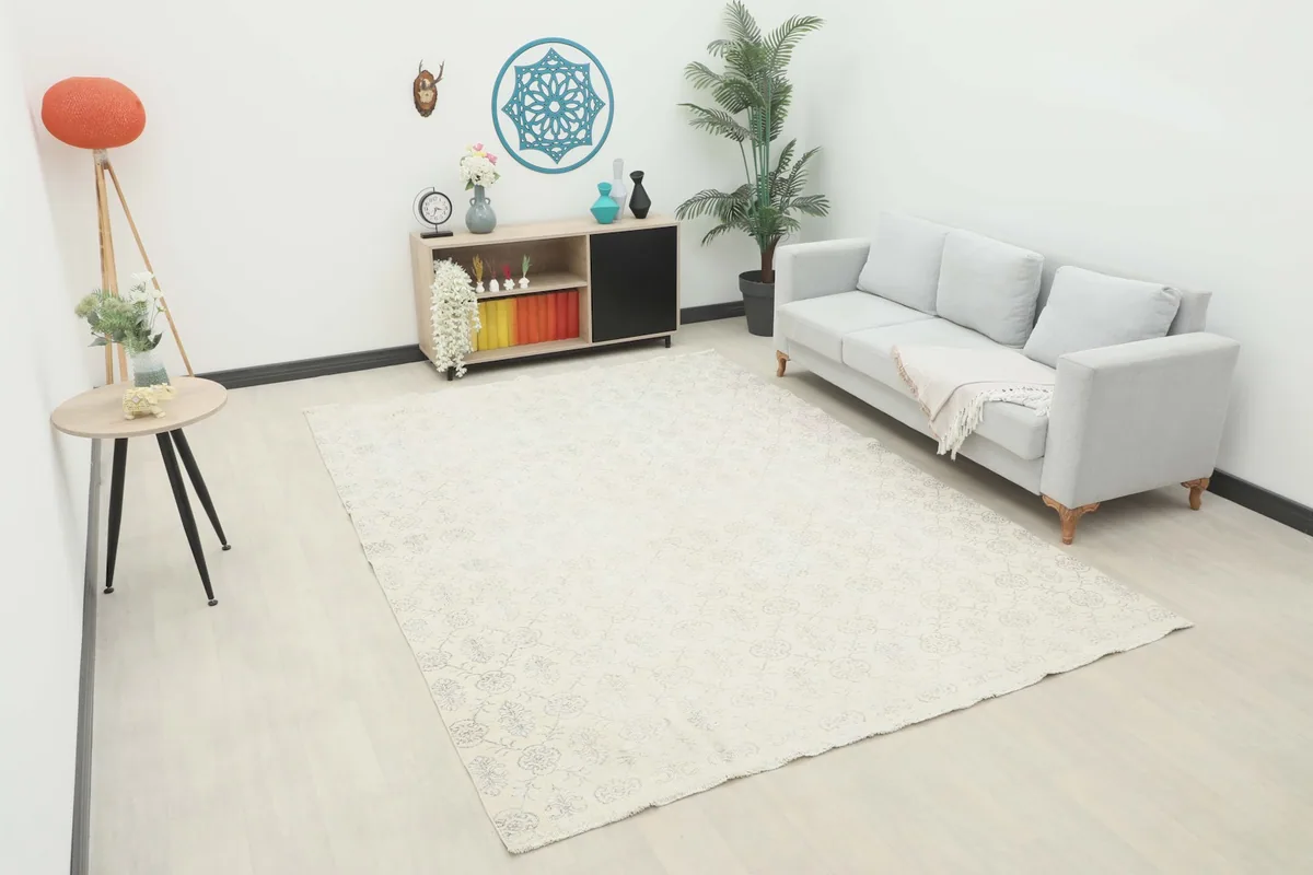 Ivory and gray floral geometric rug in a living room setting with a sofa and side table