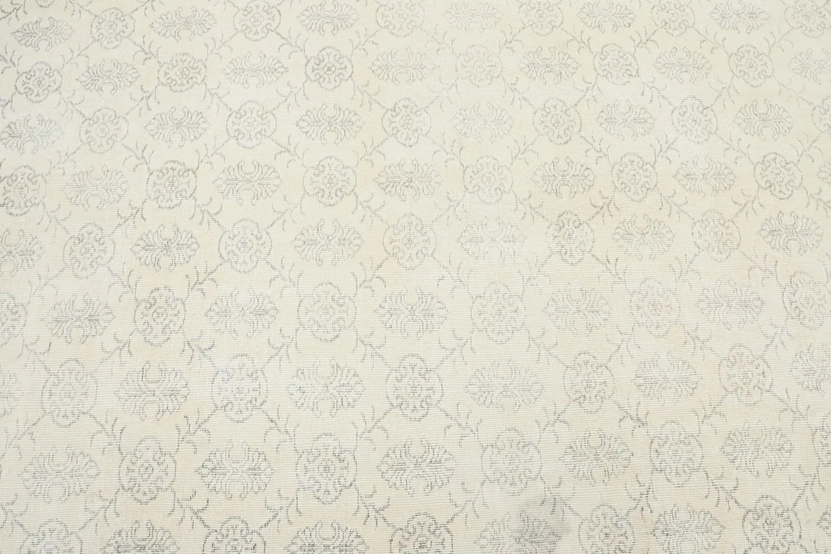 Close-up detail of the faded gray floral and geometric patterns on the ivory field