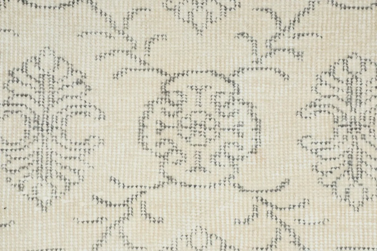 Detailed view of the hand-knotted wool pile and intricate gray motifs