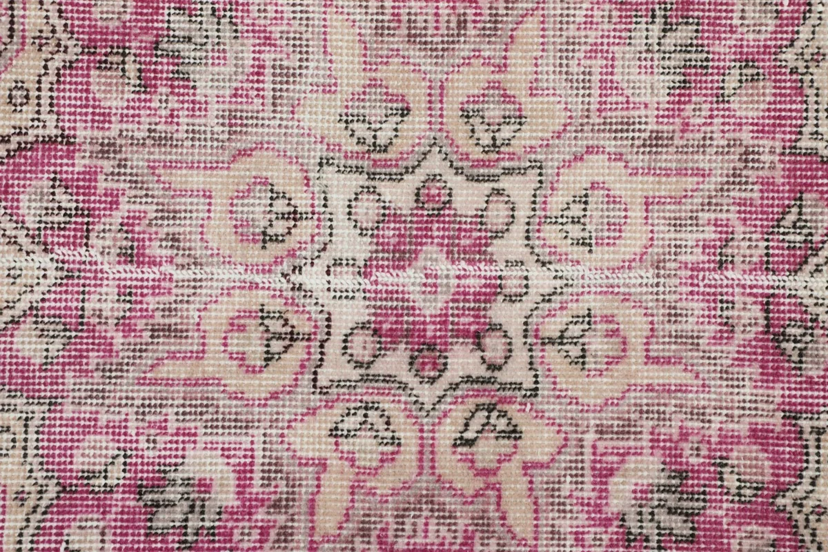 Macro detail of the hand-knotted wool pile showing intricate rose and beige patterns