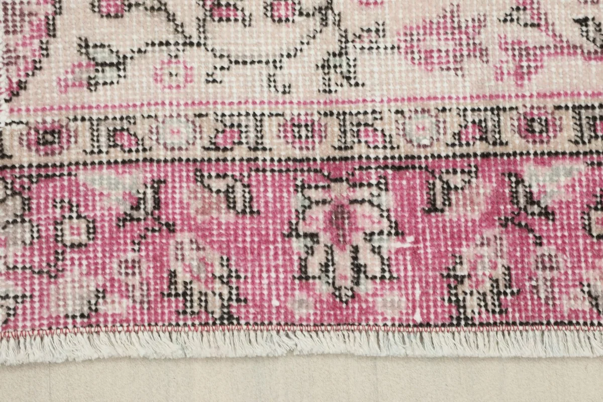 Close-up of the rug's short white fringe and the rose patterned border